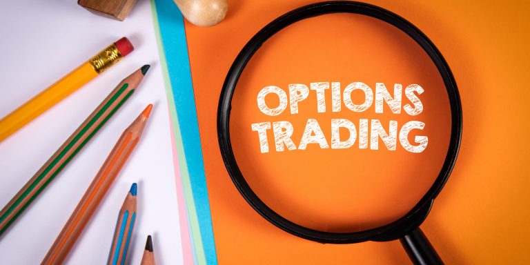 OPTIONS TRADING. Magnifying glass and office supplies on an orange background