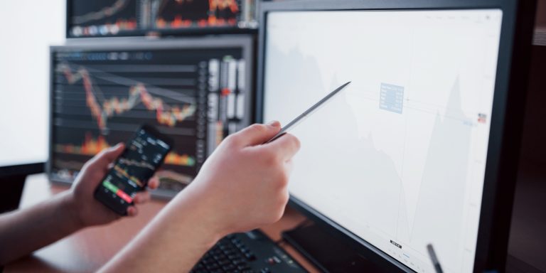 Analyzing data. Close-up of young businessman pointing on the data presented in the chart with pen while working in creative office